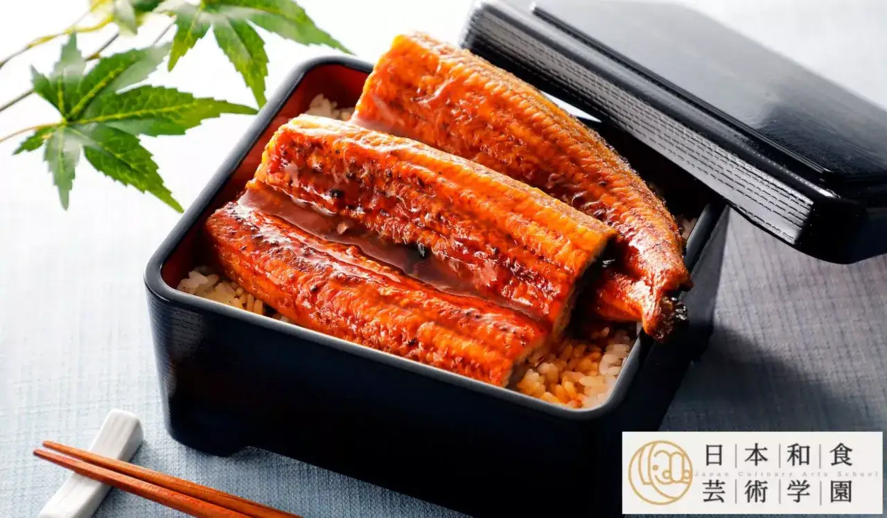 Pyszne unagi w sosie teriyaki, podane na ryżu w czarnym, lakierowanym pudełku. Obok pałeczki i liście klonu.