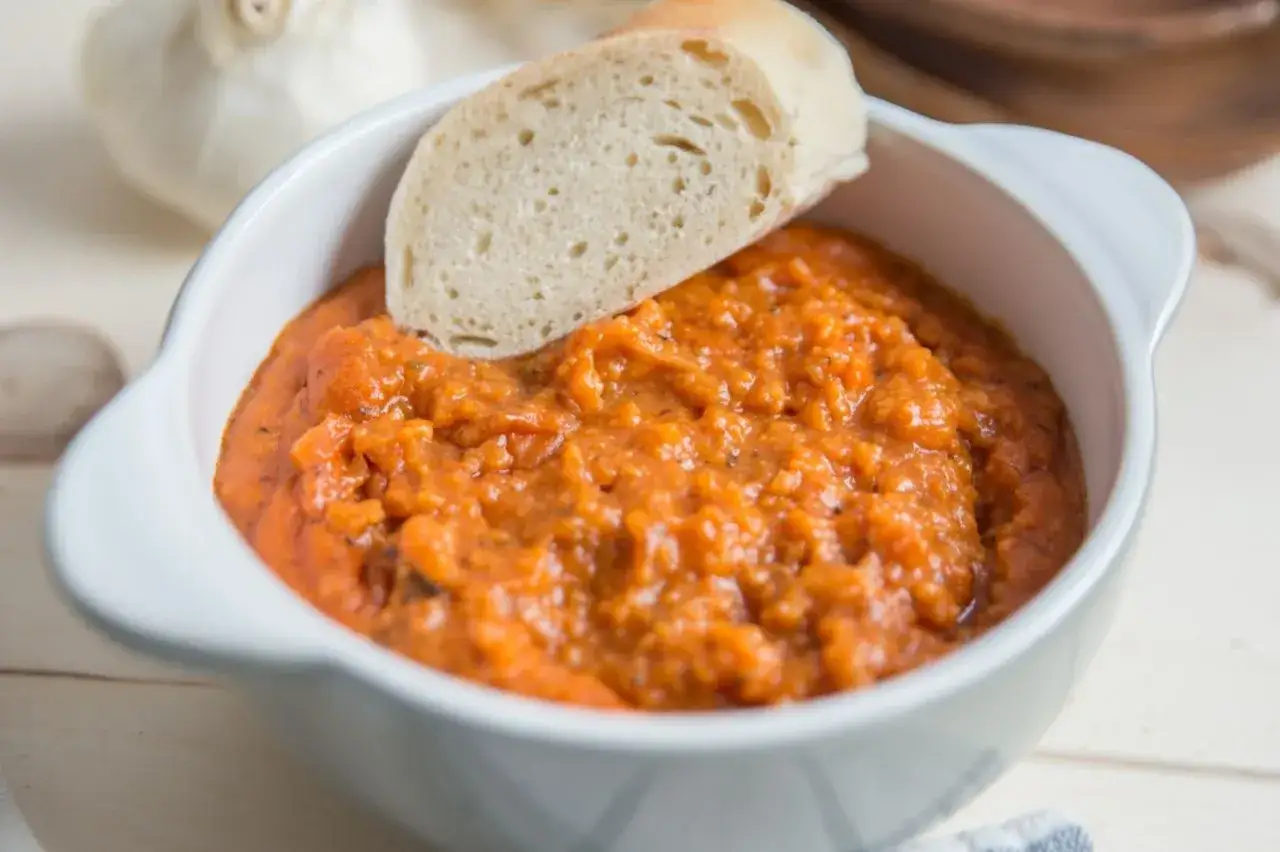 Pyszne pane e pomodoro w białej miseczce, z kawałkiem chleba. Idealna przekąska.