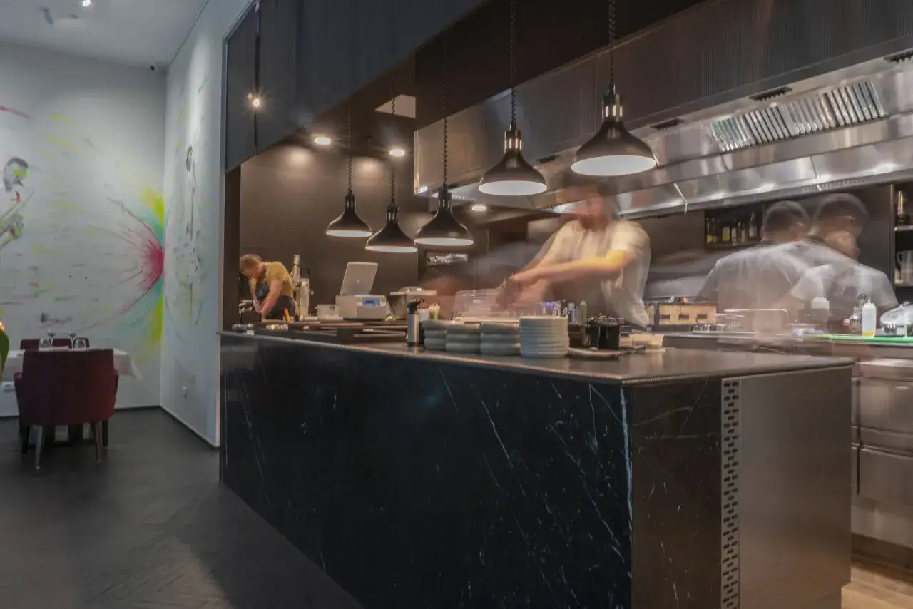 W atelier Amaro kucharze w ruchu tworzą kulinarną magię. W tle kolorowy mural.