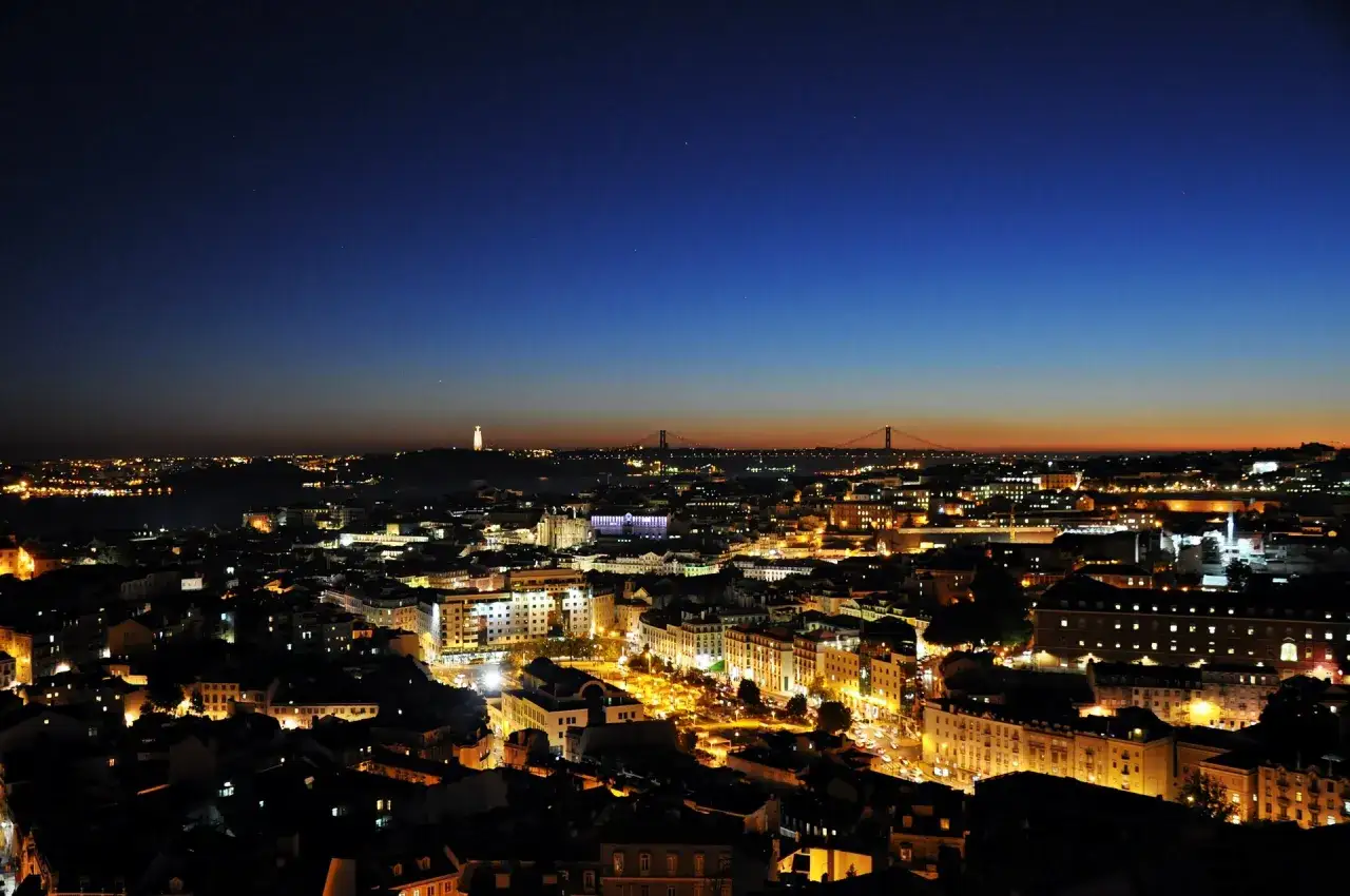 Nocny widok na Lizbonę z dzielnicy Bairro Alto. W oddali mosty i pomnik Chrystusa Króla.