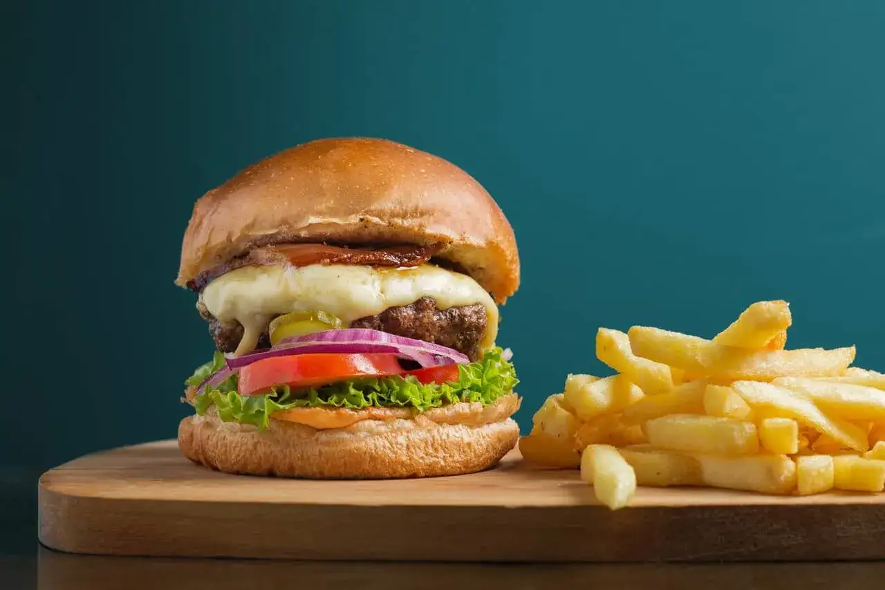 Soczysty burger z serem i frytkami, idealny na krakowskie krowarzywa.