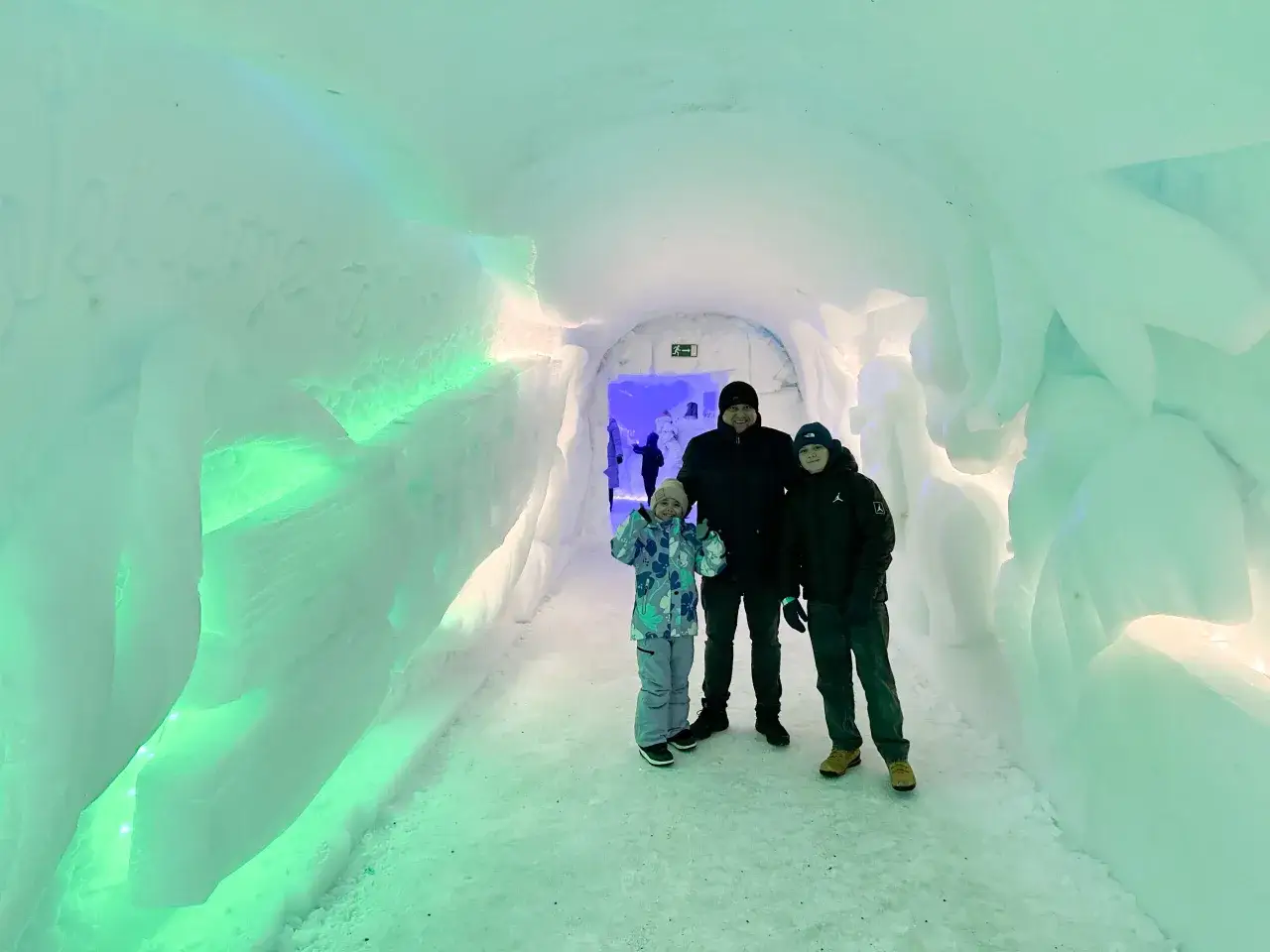 Rodzina w lodowym tunelu, który wygląda jak wejście do wioski Świętego Mikołaja.