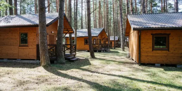 Drewniane domki letniskowe w lesie, idealne na wypoczynek nad jeziorem. Roś.